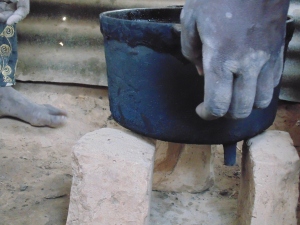 The stones are spaced evenly seven finger lengths apart from each other. The pot is then balanced on top of the stones. The stove will be constructed form-fitting  the stones and pot.
